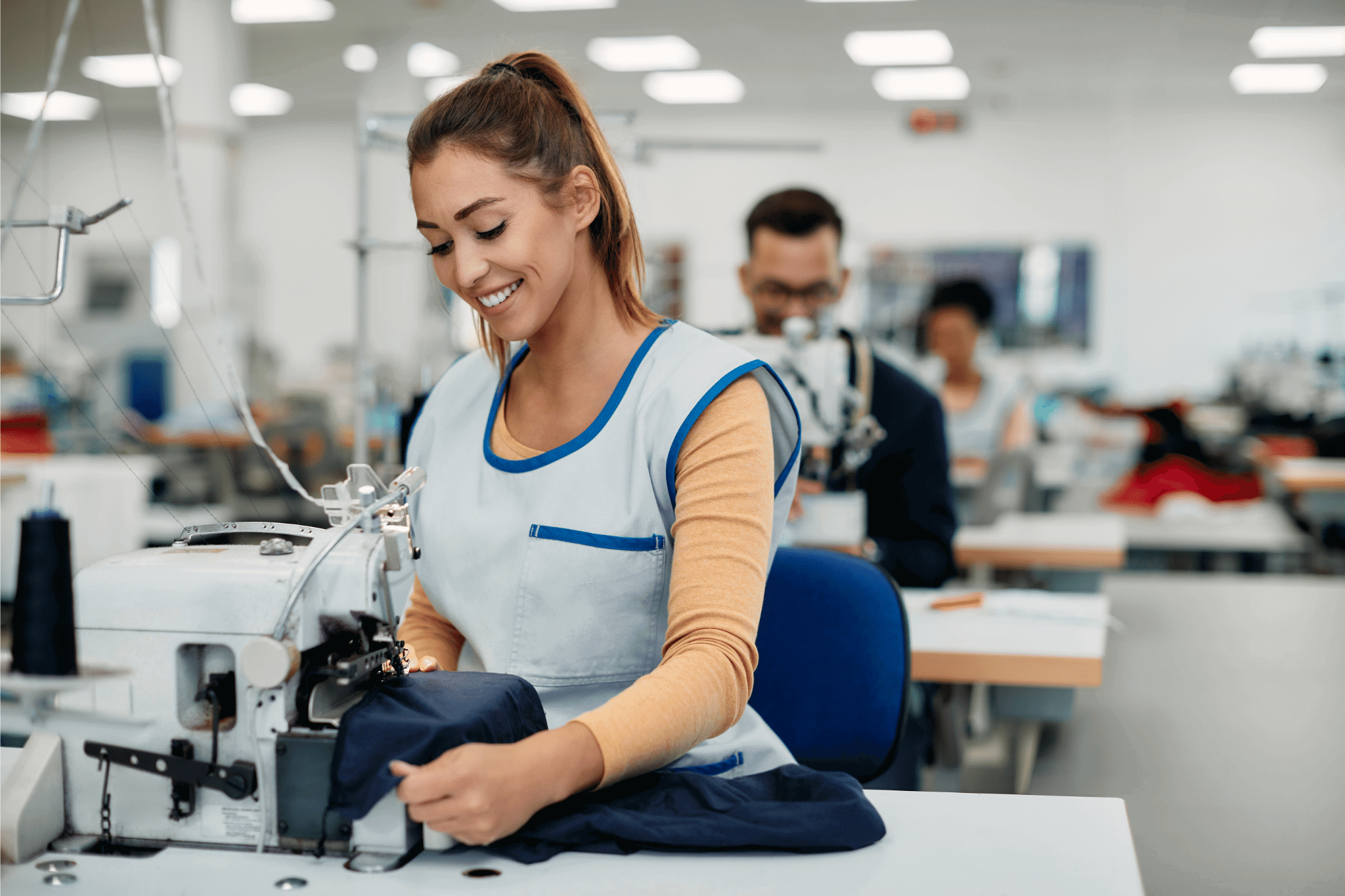 The woman in a blue overall working at the ready-to-wear clothing factory.