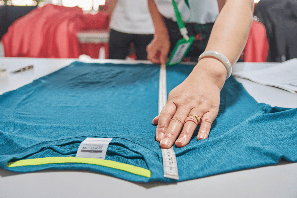 The woman employee taking measurements for a T-shirt.